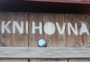 Knihovna Jabok - nápis Knihovna nastříkaný na dřevěné stěně, pod ním je umísěna placka s logem Jaboku